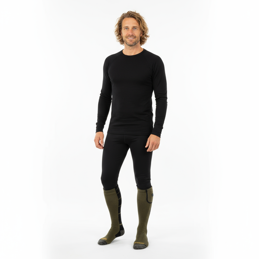 Man in black base layers wearing Wildler Heated Socks in Green pulled up to the knee, full-length studio shot