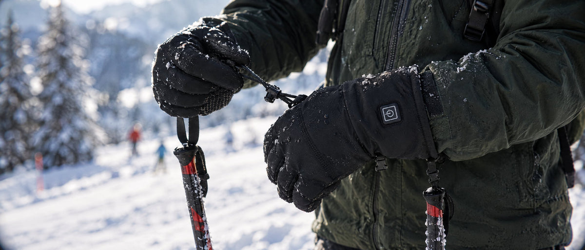 Skier tightening the cuff of Wildler heated gloves on a snowy slope