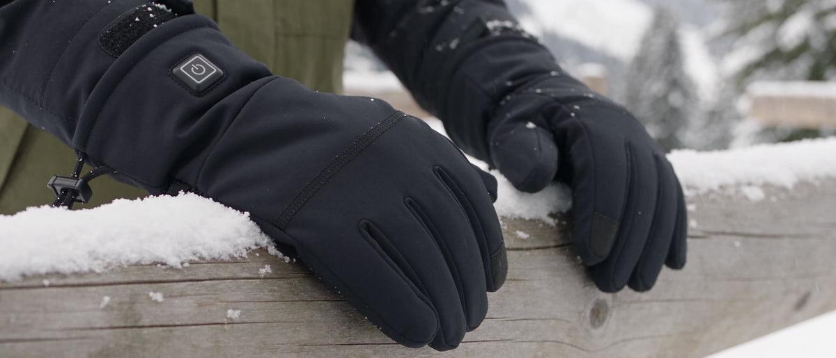 Hands in Wildler heated gloves resting on a snowy wooden rail