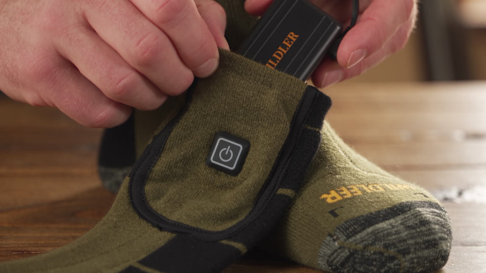 Battery sliding into the cuff pocket of a Wildler heated sock
